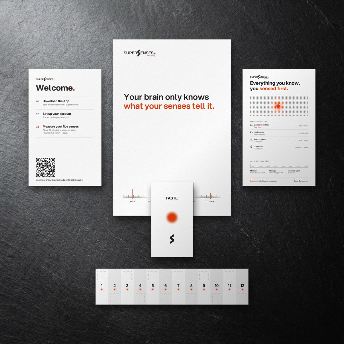 SuperSenses Five Senses Kit welcome card, envelope and test pieces on a slate background